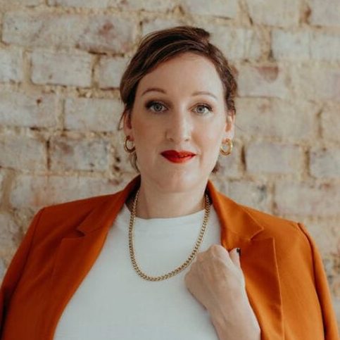 Portrait of Steffi Friedel wearing an orange blazer